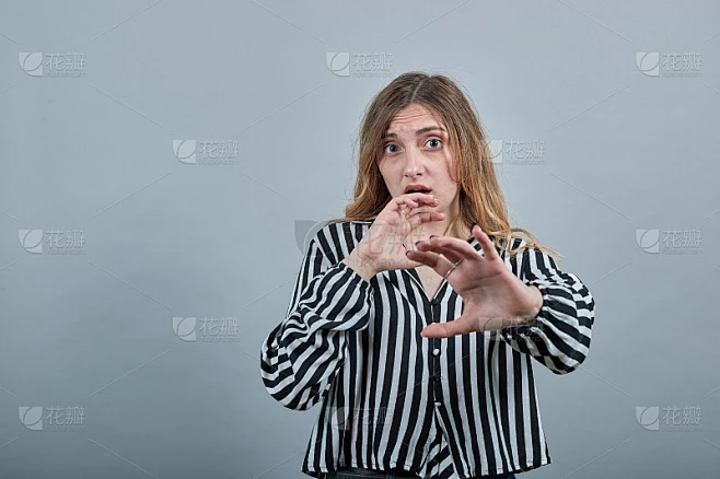 一个年轻的白种金发女人被吓到了，对着镜头露出了手掌
