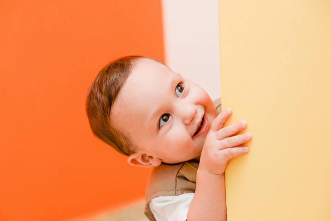 婴儿躲在米色墙旁边