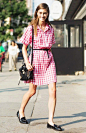 A pink gingham shirt dress is worn with black accessories.