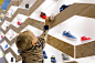 Suppakids ，一家位于德国斯图加特的儿童运动鞋售卖店。该店最大的特征是一面采用四边形+菱形语言的木材展示墙，墙面的展示区和储藏区可以自由调换，还配有彩色的面板让店主可以随心所欲的改变墙面的色彩和气氛。墙面上的构造留缝允许木盘滑轮这样的玩具从上滑到下—当然这个逗小朋友们开心的玩具不是设计的重点，设计的重点在于邀请孩子们接近展示墙，与鞋子有近距离的接触。

一个俏皮，充满乐趣的运动鞋零售店设计。