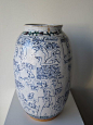 This may contain: a blue and white vase sitting on top of a table next to a wall with writing all over it