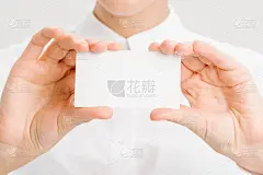 一个穿着白色办公室衬衫的女孩拿出一张名片。亲密的肖像。