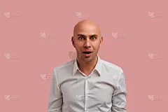 不能。兴奋感兴趣的秃顶的人与刚毛，保持张嘴，反应从对话者令人震惊的消息。穿着白衬衫，在粉红色的背景下