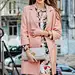 Free photo portrait of attractive stylish smiling woman walking city street in pink coat and floral dress