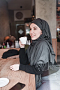 戴着头巾微笑的穆斯林女性在餐厅喝咖啡图片下载
