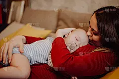 婴儿睡在妈妈的胸口和肚子上。妈妈亲吻和拥抱孩子。