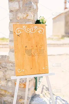 一个架子上的一根石柱旁边放着空白的木画架，上面有字母组合
