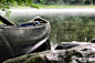 focus photo of gray and black canoe on body of water under green leaf tree