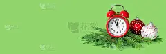 红色和白色的圣诞球，闹钟和绿纸背景上的树枝。新年前5分钟。