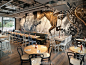 #餐厅Series# 香港的beef & liberty餐厅丨位于建筑第三层，顾客们都会被显眼的爱迪生灯的标志吸引，感受到餐厅欢迎的气氛。 餐厅中的用餐座椅围绕厨房设置，顾客可以直观地观察到食材准备的动态过程。为突出街头艺术家 cyrcle 为餐厅绘制的象征性墙绘，褐色和灰色的色调作为底色贯穿了整个设计。