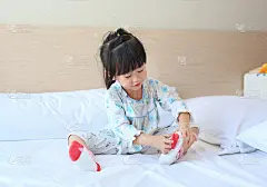 可爱的亚洲小女孩试图把袜子放在床上。
