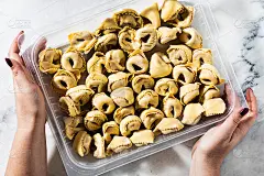 生的新鲜的自制饺子在大理石桌子和塑料盒和女性的手