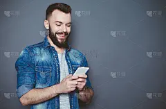 我该给你写什么?一位身穿牛仔衬衫、蓄着胡须的英俊年轻男子在灰色背景上写着一条短信。