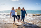 一群可爱的六十多岁的老朋友们散步，在海上洒水，玩得很开心。三个成熟健康的退休女性笑着享受退休生活和户