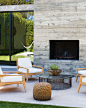 Chairs around a glass-topped coffee table beside an outdoor fireplace