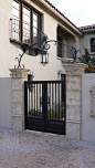 A classic and custom wrought iron entry gate, complimented by an accent arch, is an eye catching feature added to this Spanish style home.: 