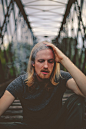 shallow focus photography of man sitting on bridge during day