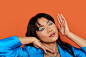 a woman in a blue shirt holding her hands up to her face