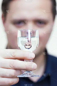 伏特加酒杯中男子倒立的肖像倒影。