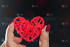 柳条红心在女性的手中，在黑暗的背景