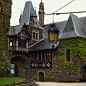 This may contain: an old stone building with ivy growing on it's sides and a clock tower in the background