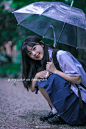 a woman kneeling down with an umbrella in her hand and looking up at the camera