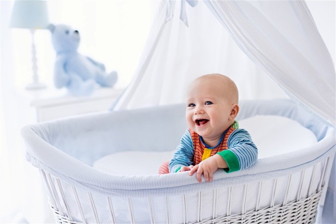 坐在婴儿床里张着嘴微笑的宝宝高清图片