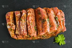 用胡椒、盐、鲜欧芹、蜂蜜、辣椒粉、孜然等腌制的生猪肉片放在黑石板上，俯视图