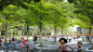 Rendering of plaza with trees and tables. Kids running in the foreground