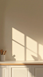 An e-commerce background picture, the picture is mostly the desktop of a white dining table, and the back background is a cupboard. The desktop is clean and there are no items, and the simple kitchen utensils are placed on the countertop of the cupboard. 