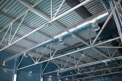 HVAC管道清洁，新建筑内的天花板上悬挂着银色保温材料的通风管道