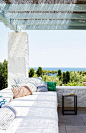 Mediterranean-style deck with built-in benches, low stucco walls and a baby blue painted pergola above.: 
