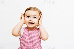A very happy small child holding her ears and looking up