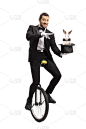魔术师骑着独轮车，用帽子和兔子表演魔术