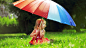 坐在绿色草地上手握五彩伞的国外女宝宝壁纸封面大图