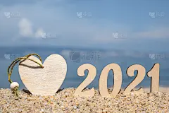 有创意的圣诞贺卡。在海滩上的2021数字与心形的天空。有选择性的重点。副本的空间。