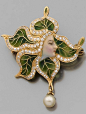 An Art Nouveau diamond, enamel and 18K gold brooch/pendant, circa 1900. Featuring a woman's face in profile framed by enamelled leaves highlighted with diamonds, suspending a pearl drop, mounted in yellow gold. 4.0 x 3.3cm. #ArtNouveau #brooch #pendant