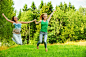 两个年轻的快乐妇女跳又笑在夏天绿色公园
