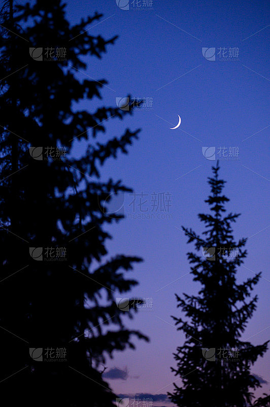 一弯新月映衬着蓝色和紫色的天空，山间宁静...