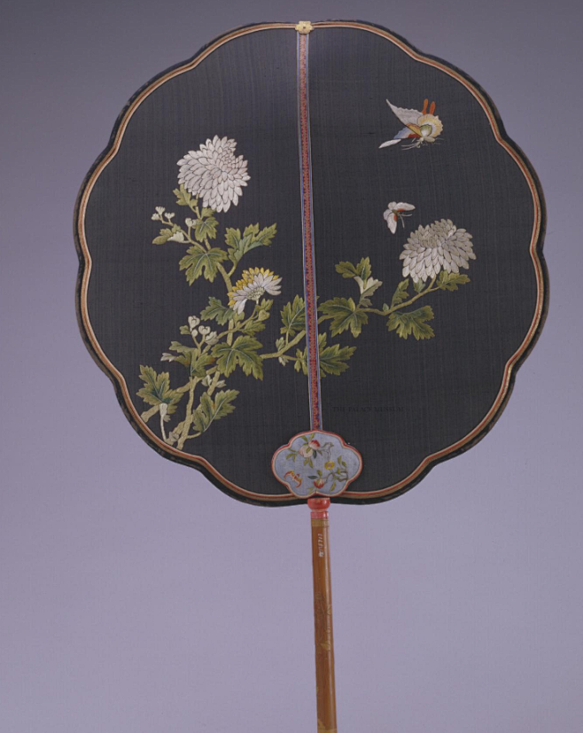 黑绸绣花蝶竹柄团扇，清，扇作十二葵瓣形，扇面黑绸地上双面绣折枝蛱蝶菊花。绣幅宛若图画，讲究虚实向背，层次分明，构图因扇骨而划分为左右二部分。其 ...