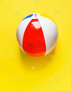 彩色条纹充气沙滩球在明亮的黄色背景。夏季运动度假海滩孩子好玩的旅游概念。设计拼贴元素文本的空白占位符