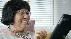 坦率的亚洲退休老太太使用平板电脑在线转账或金融支付和阅读文字，微笑或笑与快乐和积极。资深亚洲与数字技