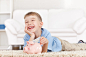 Little boy and his mother inserting money into piggy bank