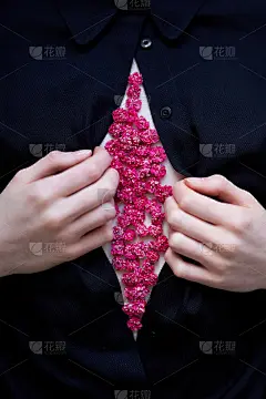 粉红色的花在女人身上。双手敞开黑色衬衫