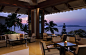 Open-air restaurant seating with ocean views surrounded by tropical trees