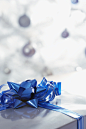 圣诞吊球背景前的蓝色装饰花朵礼品盒
