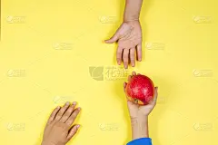 一个小孩的手从另一个小孩的手里接过红苹果