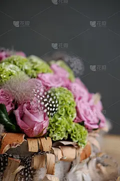 美丽的春天花束特写与粉红色的玫瑰和绿色康乃馨，装饰羽毛和桦树皮。