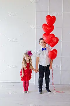 漂亮的小女孩和男孩，拿着心形的红色气球