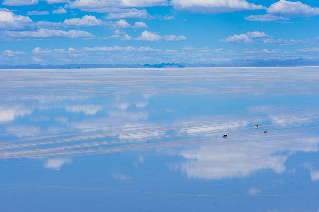 「天空の鏡と呼ばれる雨季のウユニ塩湖を横...